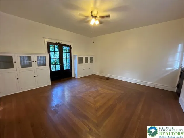 a view of an empty room with a window and wooden floor
