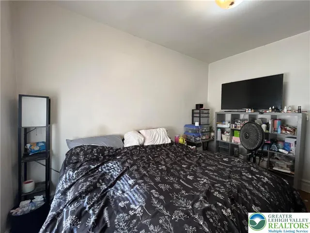 a bedroom with a bed a flat screen tv and chairs