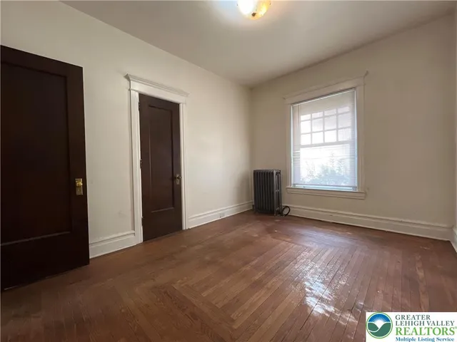 an empty room with wooden floor cabinet and windows