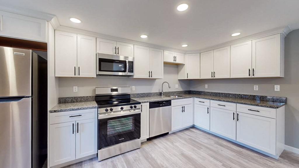 a kitchen with stainless steel appliances granite countertop white cabinets granite counter tops and a stove