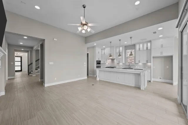 a large white kitchen with a refrigerator a sink dishwasher a oven and a dining table with wooden floor