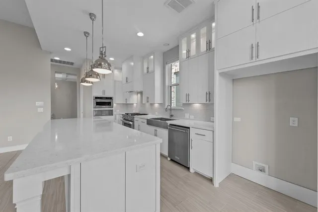 a large white kitchen with kitchen island white cabinets and stainless steel appliances