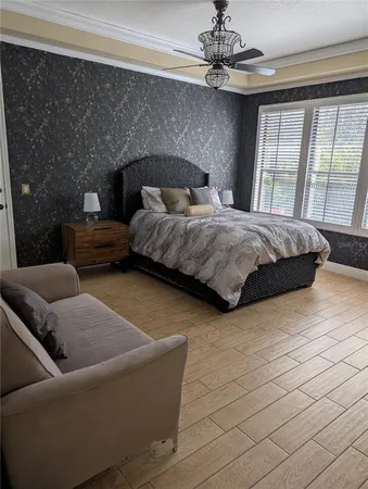 a bedroom with a bed couch chandelier and a window