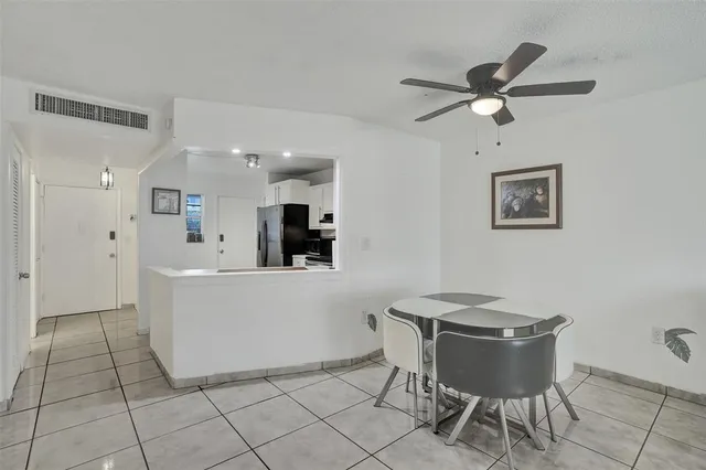 a view of kitchen with stainless steel appliances kitchen island granite countertop a refrigerator a stove top oven a sink with island and chairs