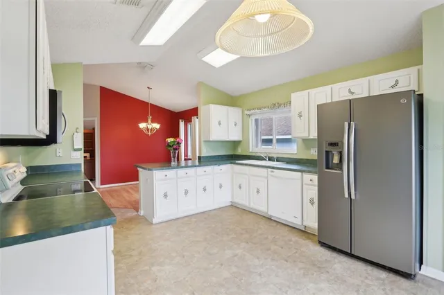 a large kitchen with stainless steel appliances granite countertop a refrigerator a stove and a sink