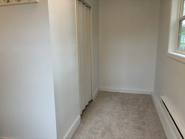 an empty room with wooden floor chandelier and windows