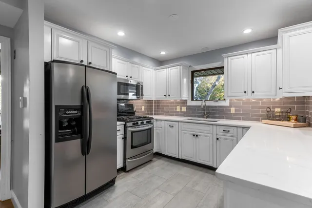 a kitchen with granite countertop stainless steel appliances cabinets a sink and a window