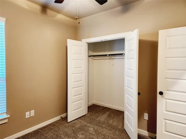 an empty room with closet and a ceiling fan