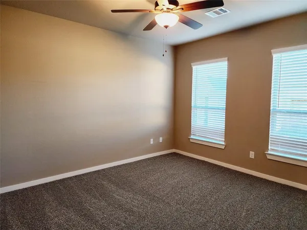 an empty room with windows and fan