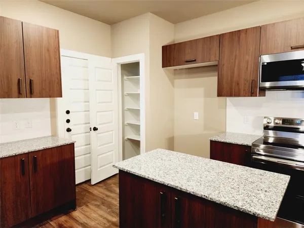 a kitchen with stainless steel appliances kitchen island granite countertop a refrigerator and a stove top oven