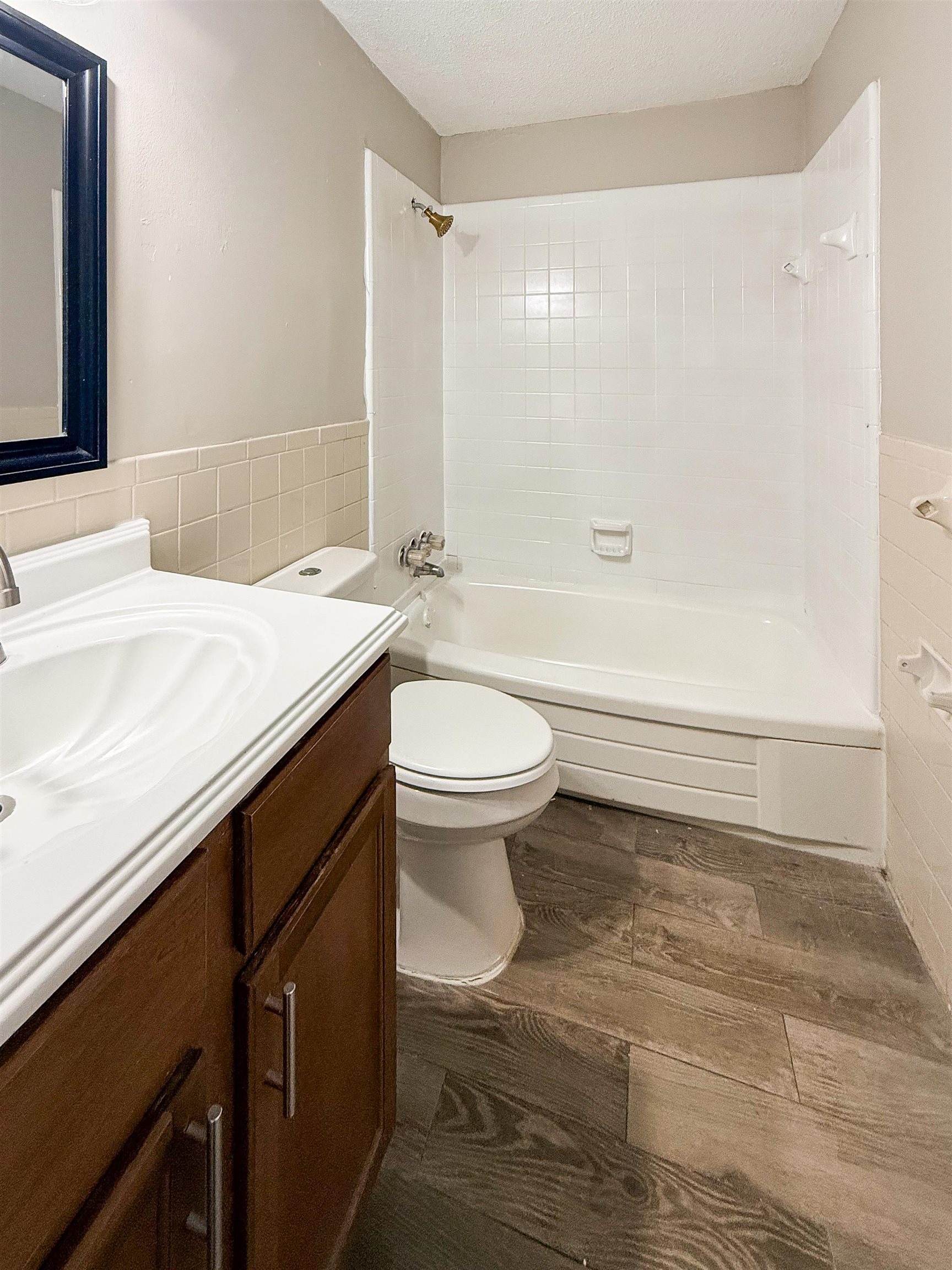 655 West Raines Road Memphis, TN 38109 - Photo 16 of 18 Full bathroom featuring vanity, tile walls, shower combination, dark wood-type flooring, and wainscoting
