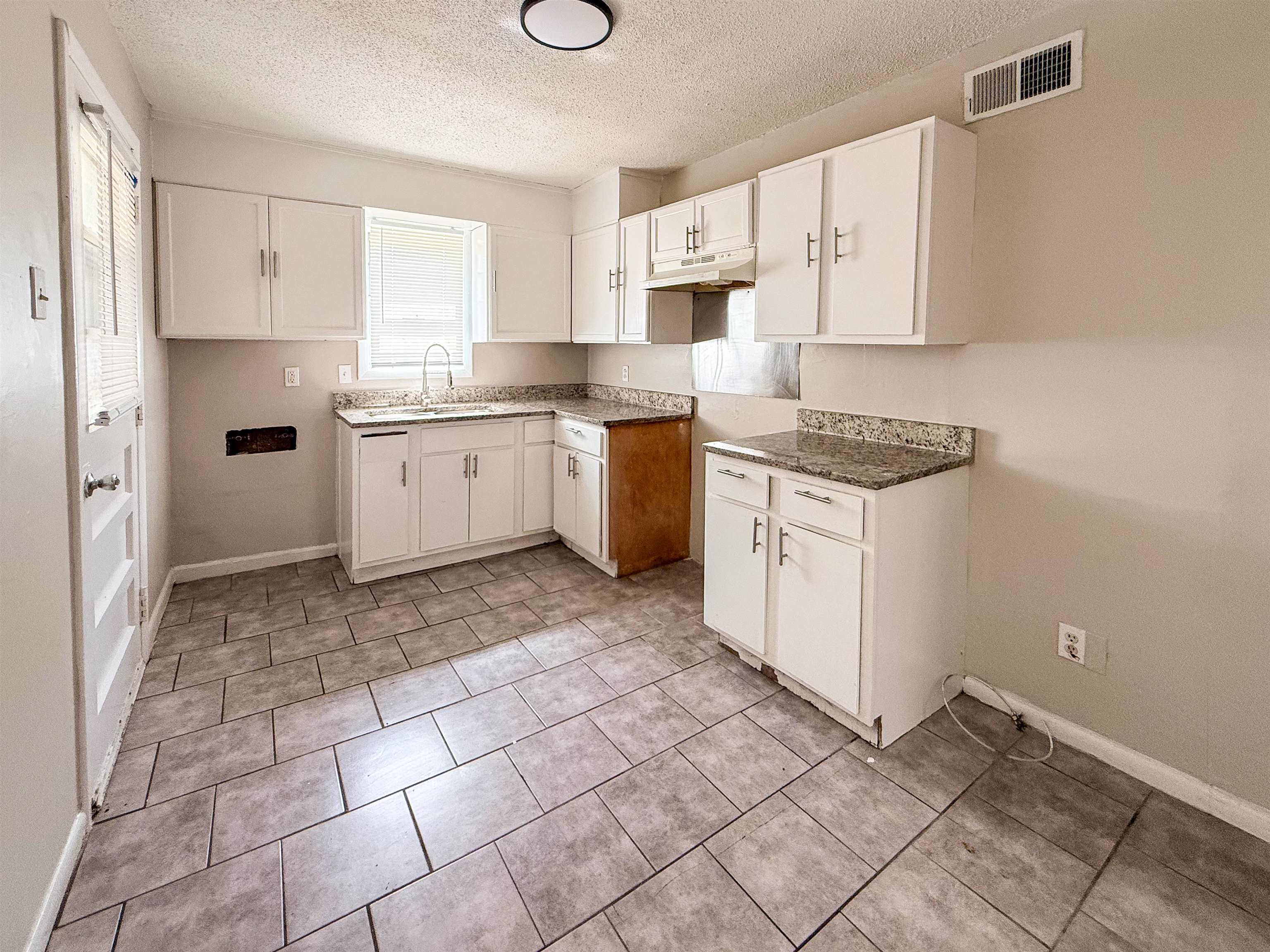655 West Raines Road Memphis, TN 38109 - Photo 6 of 18 Kitchen featuring white cabinetry, a textured ceiling, and light tile patterned flooring