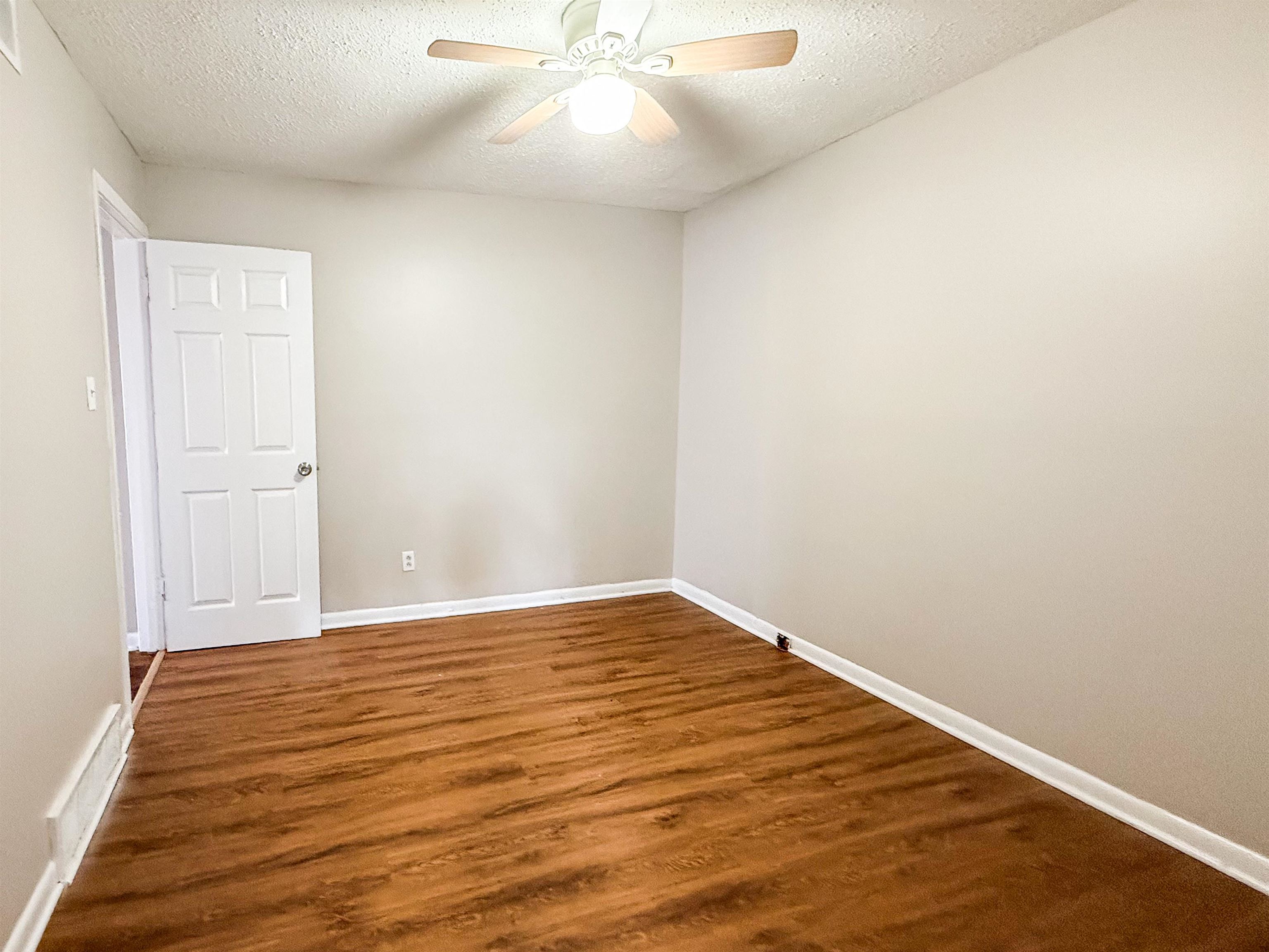 655 West Raines Road Memphis, TN 38109 - Photo 9 of 18 Empty room featuring a textured ceiling, dark wood-type flooring, and ceiling fan