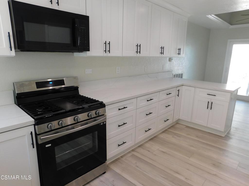 559 Stoney Peak Court Simi Valley, CA 93065 - Photo 4 of 62 a kitchen with white cabinets stainless steel appliances and wooden floor