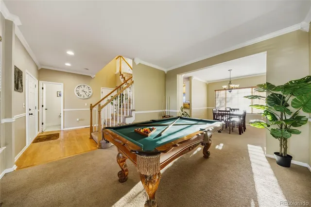 a living room with furniture pool table and a potted plant