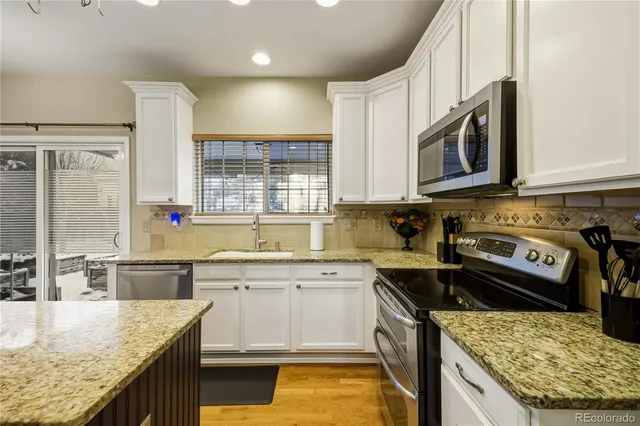 a kitchen with stainless steel appliances granite countertop a sink stove and cabinets