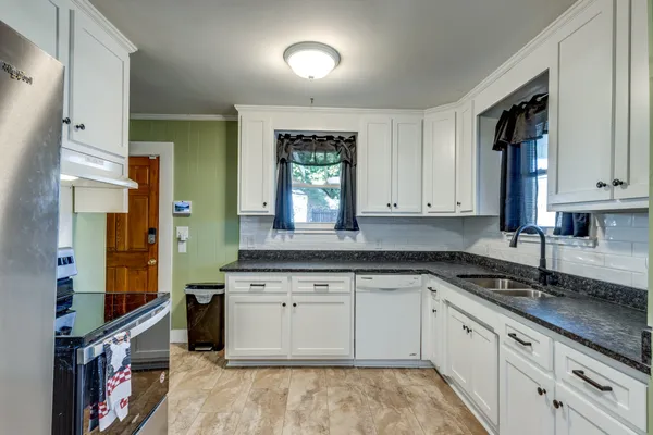 a kitchen with granite countertop a sink stainless steel appliances and cabinets