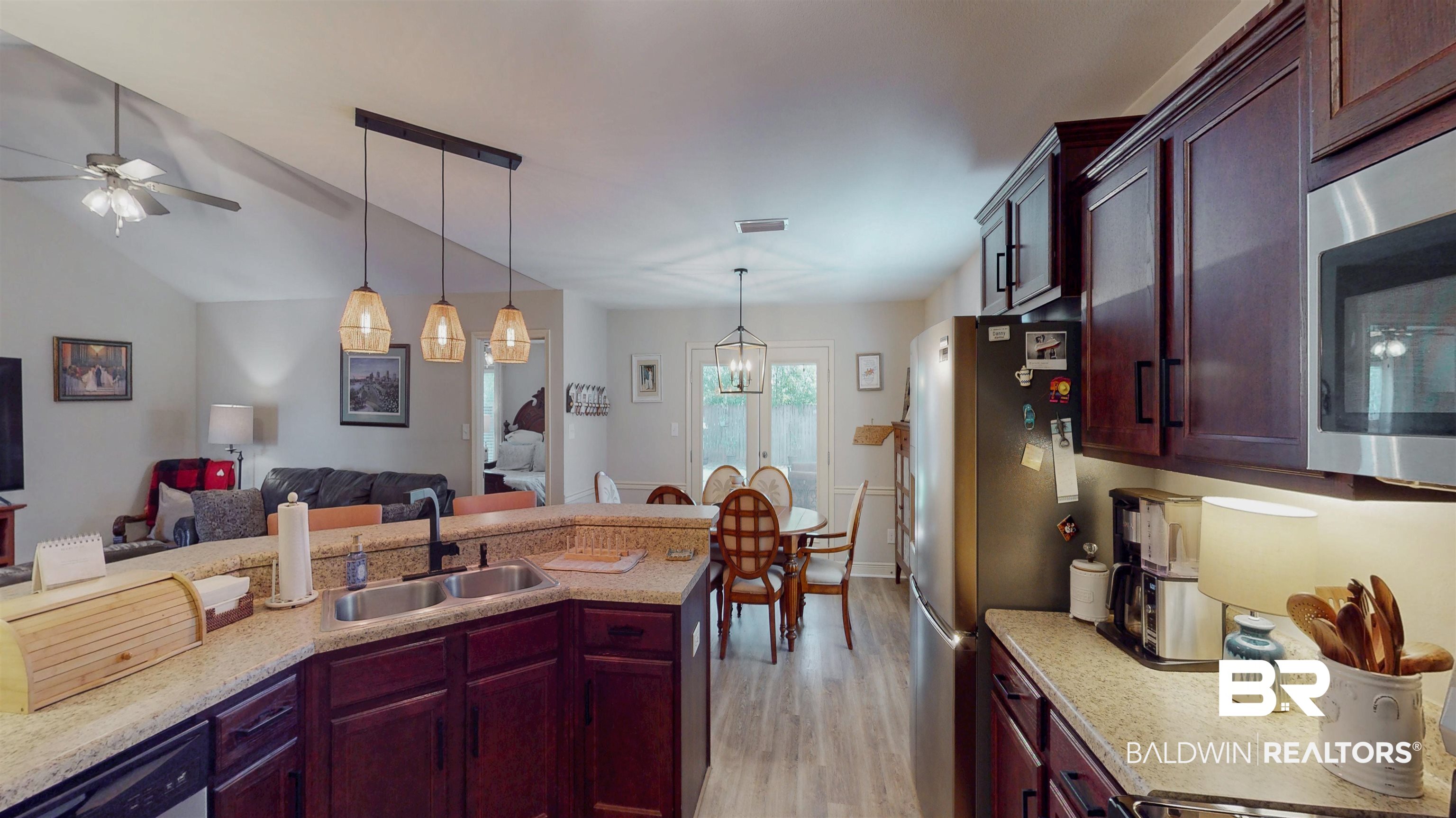 1304 Majesty Loop Foley, AL 36535 - Photo 41 of 44 Kitchen featuring bold wood finish cabinetry, open floor plan, stainless steel appliances, light stone counters, and vaulted ceiling
