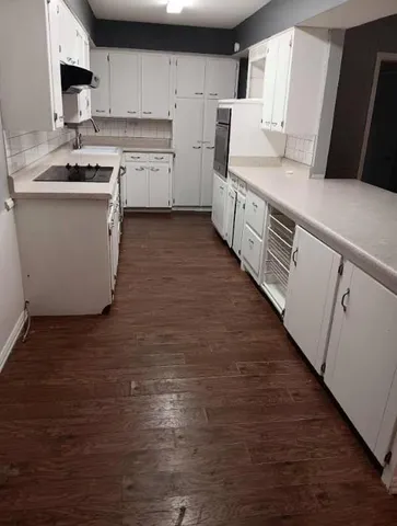 a kitchen with stainless steel appliances a sink wooden floor and a refrigerator