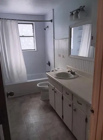 a bathroom with a granite countertop sink toilet and mirror