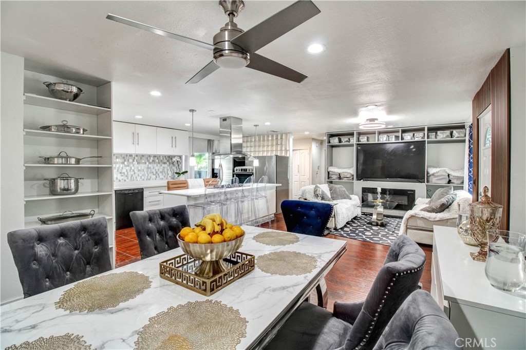 a living room with stainless steel appliances furniture a rug and a flat screen tv
