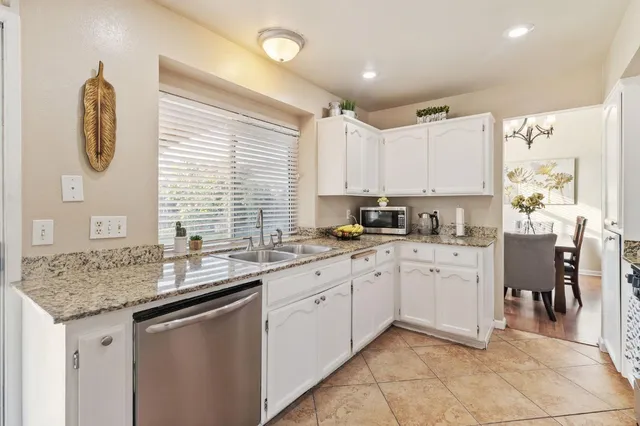 a kitchen with granite countertop a sink and a white wooden cabinets