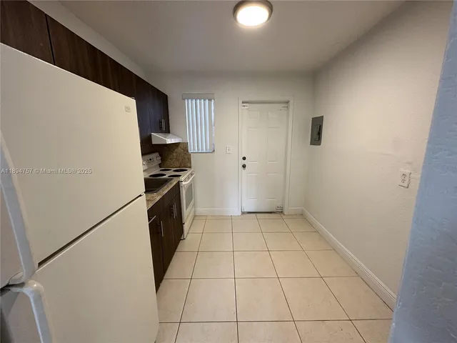 a kitchen with granite countertop a refrigerator and a stove top oven