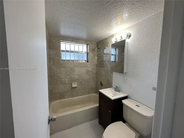 a bathroom with a bathtub shower sink vanity and toilet