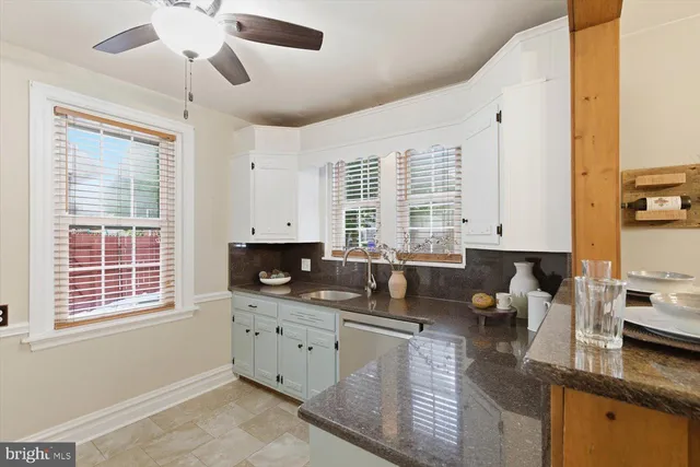 a kitchen with granite countertop a sink a counter space appliances and cabinets