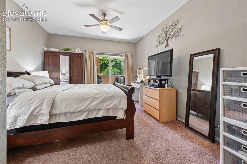 3715 Riviera Grove, Unit 101 Colorado Springs, CO 80922 - Photo 25 of 36 Carpeted bedroom featuring a ceiling fan with integrated lighting, a sliding glass door, and neutral wall tones