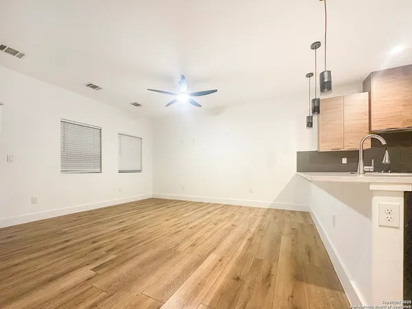 a view of a kitchen with kitchen island a sink wooden floor and a chandelier