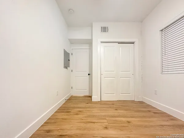 a view of an empty room with wooden floor and closet