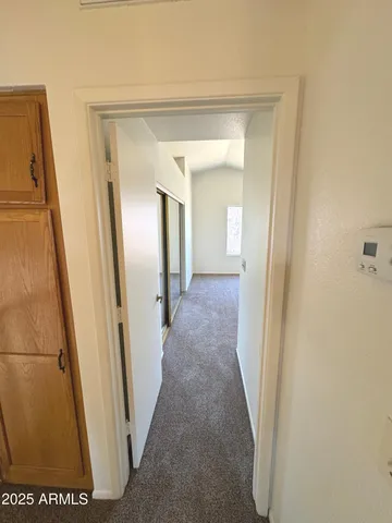 a view of a hallway with wooden floor and a bathroom