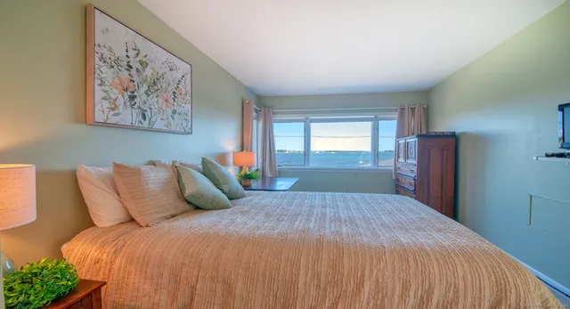 a bedroom with a bed couch and windows