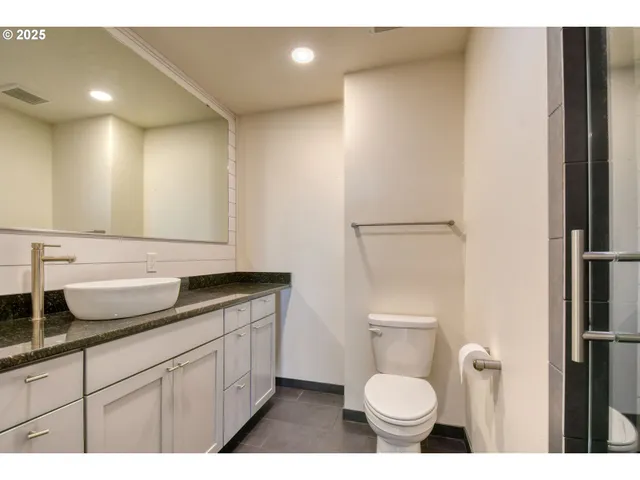 a bathroom with a granite countertop toilet sink and mirror