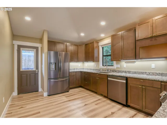 a kitchen with granite countertop stainless steel appliances refrigerator sink and cabinets