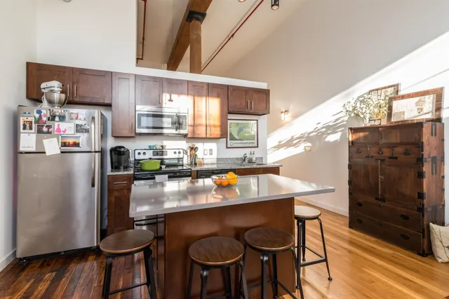 a kitchen with stainless steel appliances granite countertop a table chairs stove and refrigerator