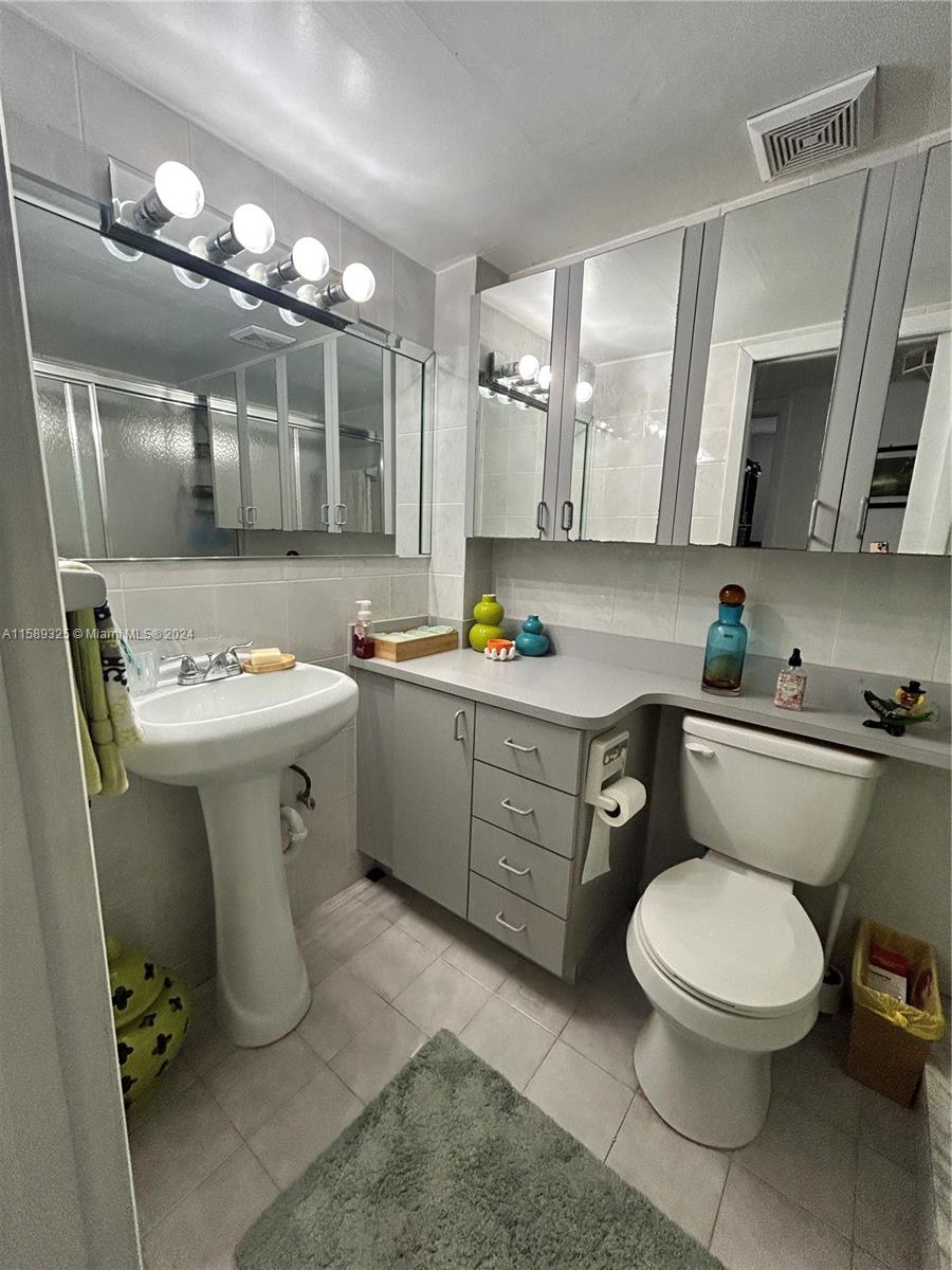5050 Northwest 7th Street, Unit PH1 Miami, FL 33126 - Photo 18 of 36 a bathroom with a toilet sink and mirror
