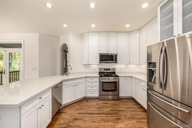 a kitchen with stainless steel appliances kitchen island a refrigerator sink and white cabinets