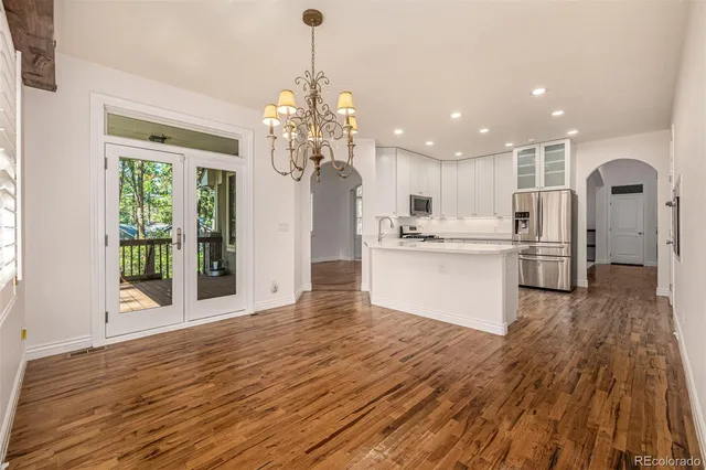 a kitchen with stainless steel appliances granite countertop a refrigerator a stove and a sink with wooden floor