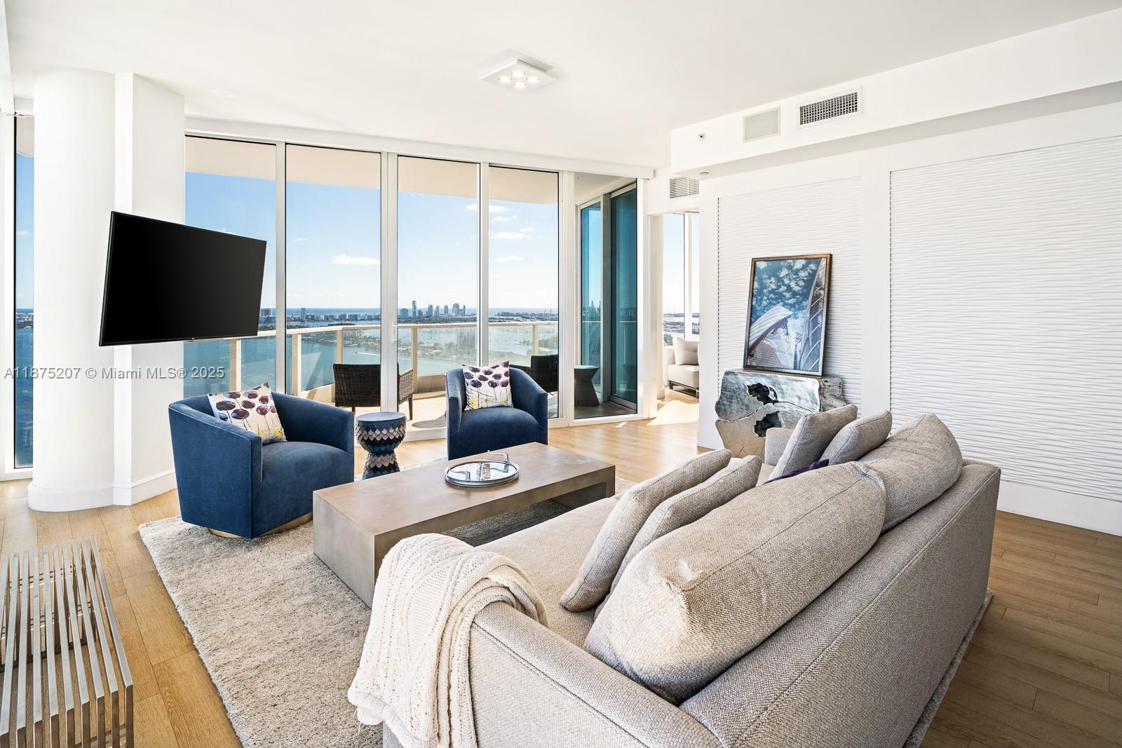 2020 North Bayshore Drive, Unit 4101 Miami, FL 33137 - Photo 2 of 23 a living room with furniture a flat screen tv and a floor to ceiling window