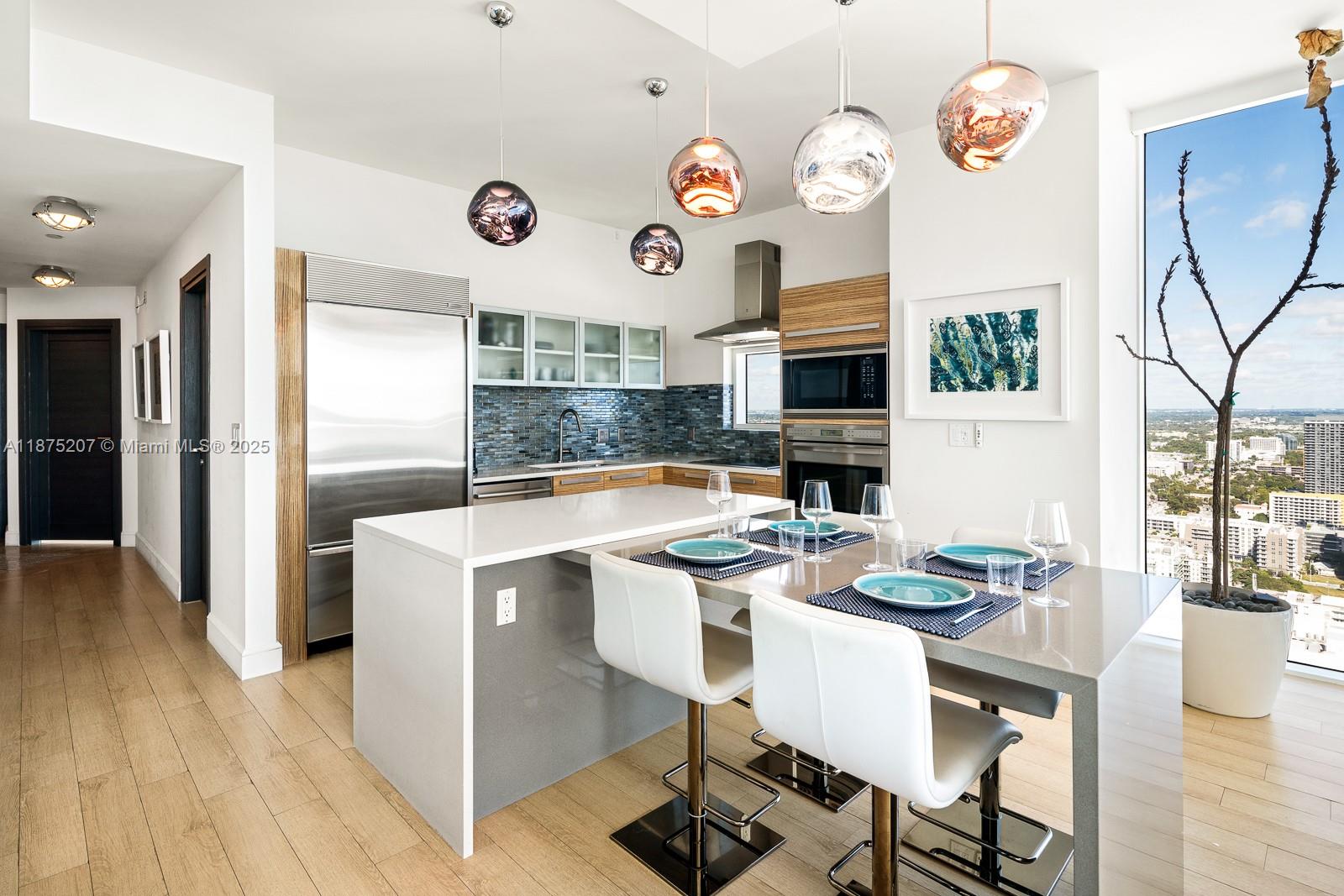 2020 North Bayshore Drive, Unit 4101 Miami, FL 33137 - Photo 8 of 23 a kitchen with a refrigerator a stove top oven a dining table and chairs with wooden floor