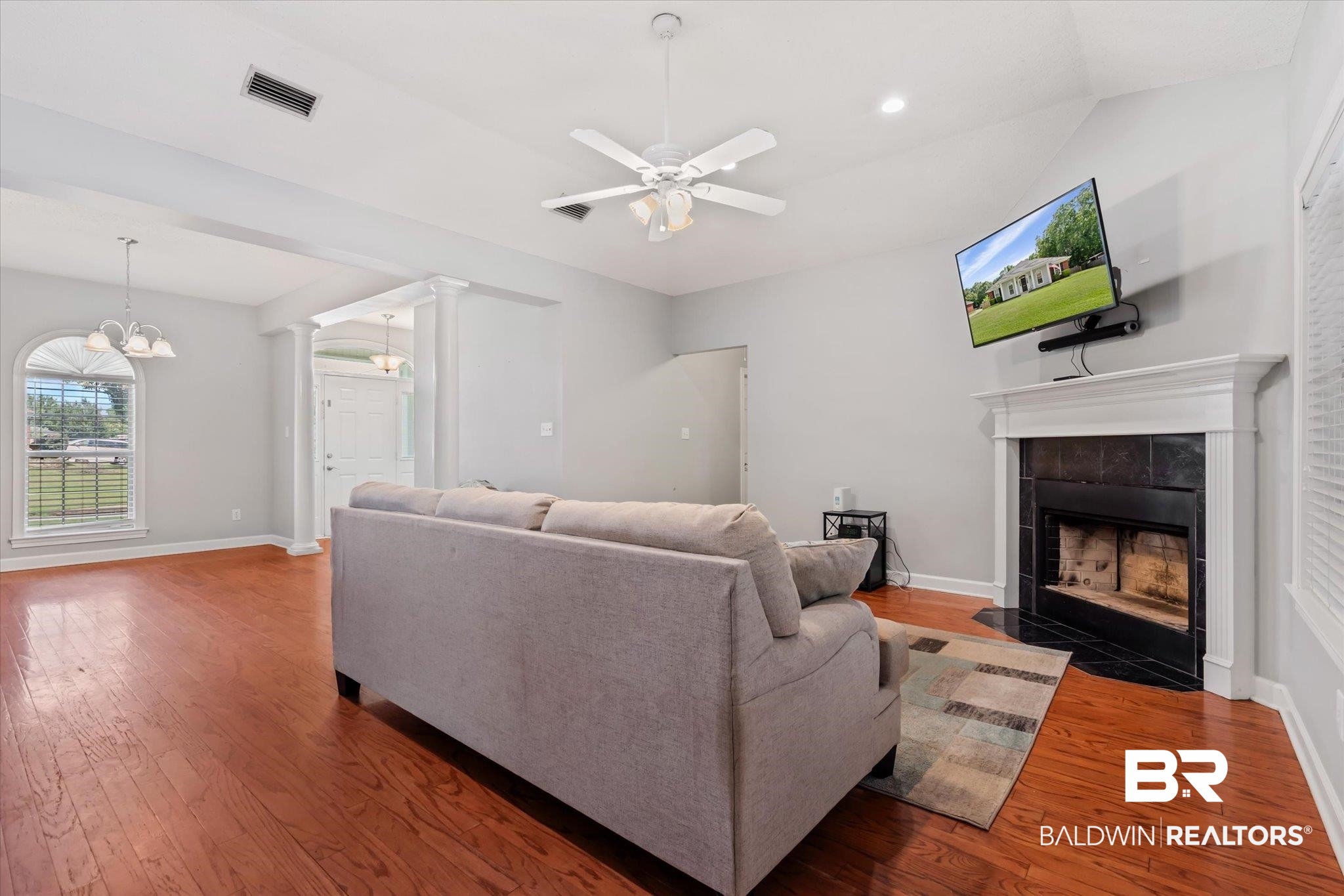 2320 Sequoya Trail Mobile, AL 36695 - Photo 5 of 20 Living room featuring ceiling fan with notable chandelier, a tile fireplace, hardwood / wood-style floors, and ornate columns