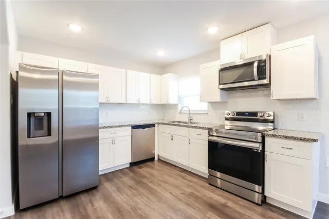 a kitchen with stainless steel appliances granite countertop a stove a sink and a refrigerator
