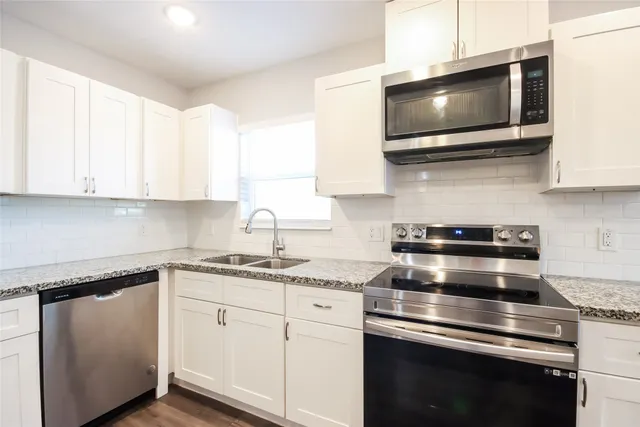 a kitchen with stainless steel appliances granite countertop a sink a stove and microwave