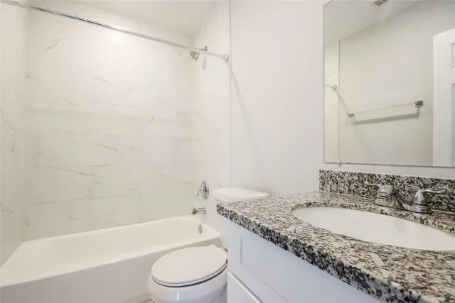a bathroom with a granite countertop sink toilet and bathtub