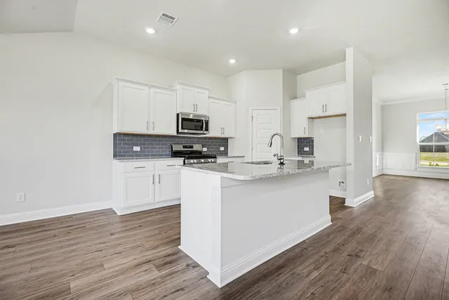 a kitchen with white cabinets and appliances