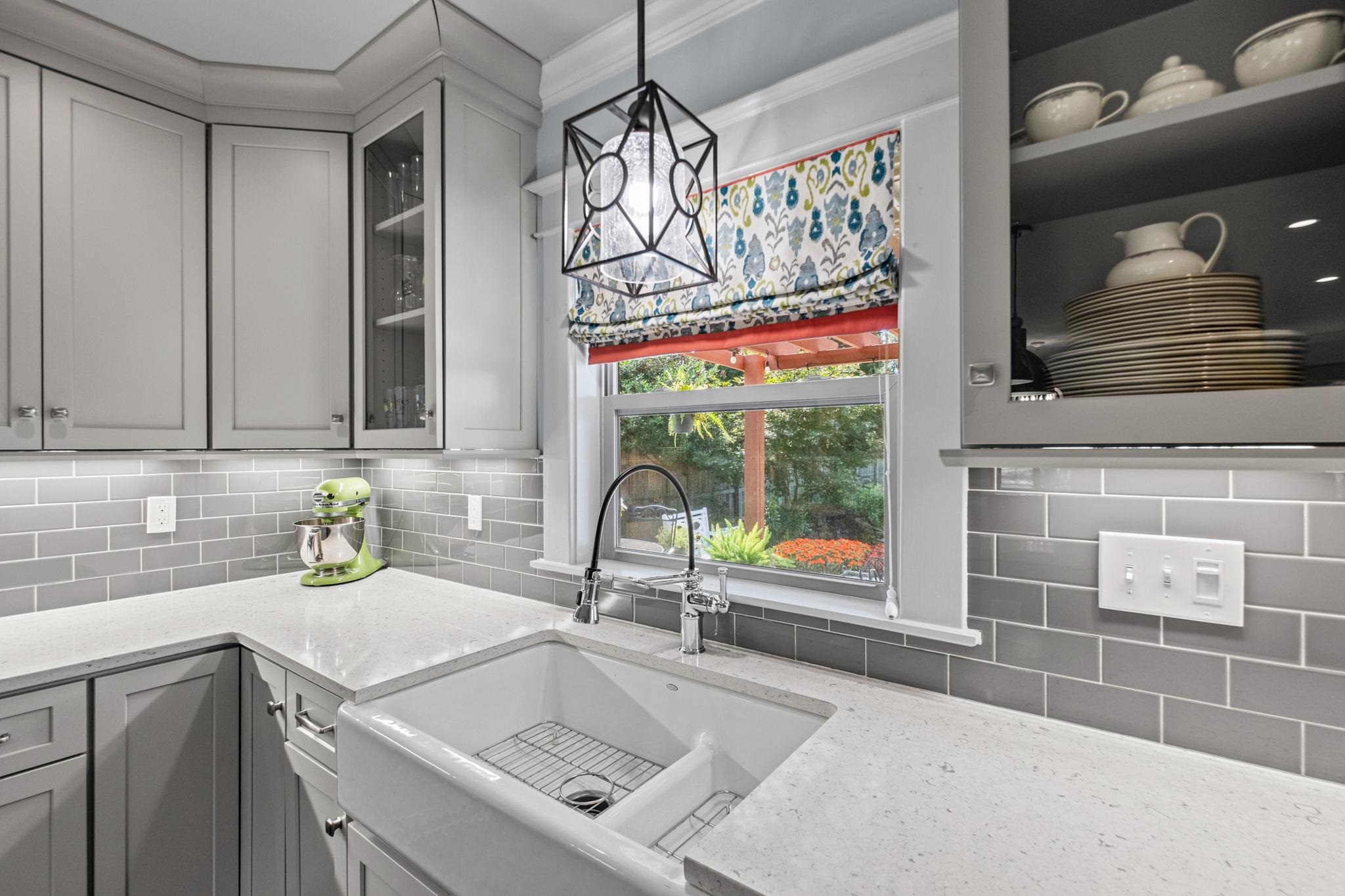 5079 Walnut Grove Road Memphis, TN 38117 - Photo 15 of 40 White farmhouse sink with a black gooseneck faucet, light grey shaker-style cabinetry, grey subway tile backsplash, and light-toned countertops