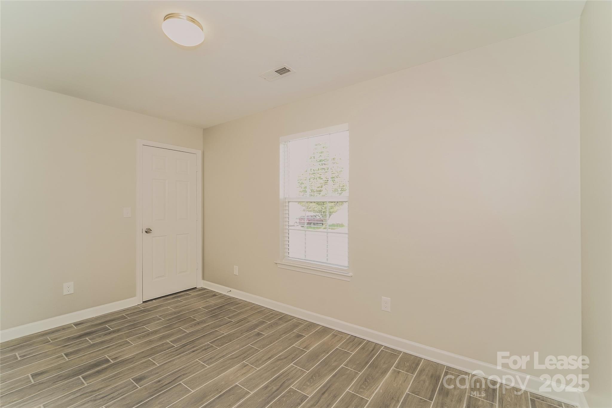 3931 Bitterroot Court Charlotte, NC 28269 - Photo 13 of 16 a view of an empty room with wooden floor and a window