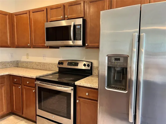 a kitchen with stainless steel appliances kitchen island a refrigerator sink and microwave